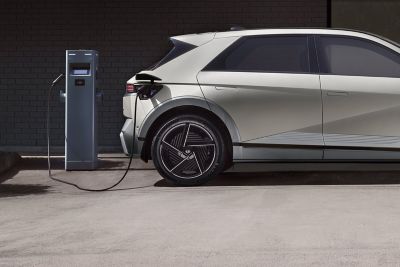 Hyundai KONA Electric en cours de recharge sur une borne installée sur une place de parking.