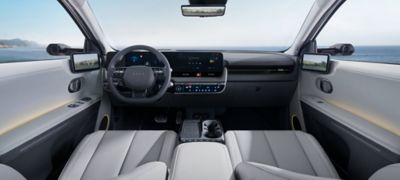 Interior of new Hyundai IONIQ 5 cockpit showing the steering wheel, dashboard and both front seats.