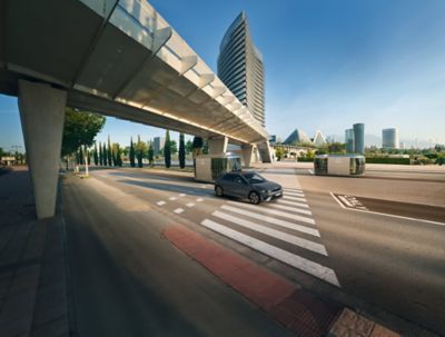 Hyundai IONIQ 5 driving on the road under a bridge with futuristic Hyundai taxi.