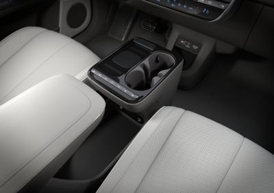 Middenconsole nieuwe Hyundai IONIQ 5, met zicht op oplaadpad smartphone, bekerhouders en knoppen voor stoelverwarming en parkeercamera.