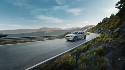 Hyundai IONIQ 5 drives driving through on the highway in the mountain.