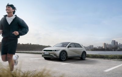 A man going for a run with a Hyundai IONIQ 5 parked in the background.