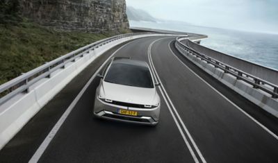 IONIQ 5 kjørende på en kystvei. Foto.