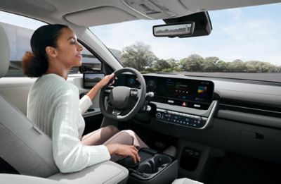 A woman in the driver's seat of the Hyundai IONIQ 5 checking the the Digital Centre Mirror.