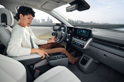 A man sitting in the driver’s seat of the IONIQ 5, looking down at the centre console.
