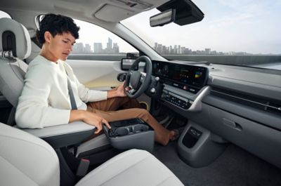 Un hombre sentado en el asiento del conductor del Hyundai IONIQ 5 mira la consola central.