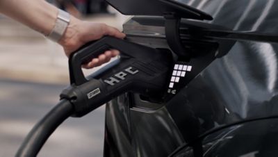 A person plugging the charging cable into the side of the Hyundai IONIQ 5 electric midsize CUV.