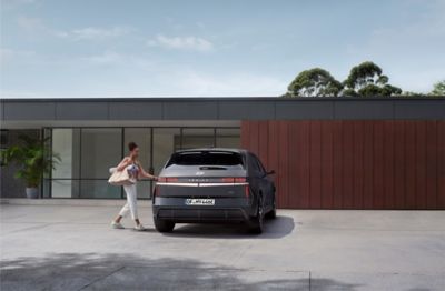 A woman opening the door of Hyundai IONIQ 5 N Line parked in front of the house.