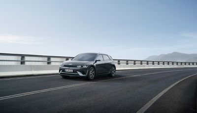 Front three-quarters view of the new Hyundai i30 Hatchback in grey, parked outside a modern house.