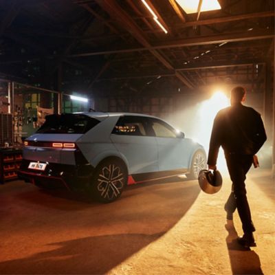 A man carrying a safety helmet walking towards a  Hyundai IONIQ 5 N.