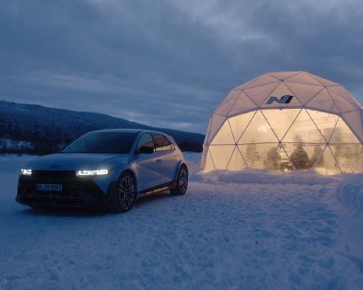 Crépuscule dans un décor hivernal, scientifiques vus à travers une tente transparente, la IONIQ 5 N garée devant.