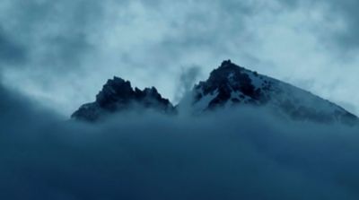 Snowy mountain tops rising above dark clouds.
