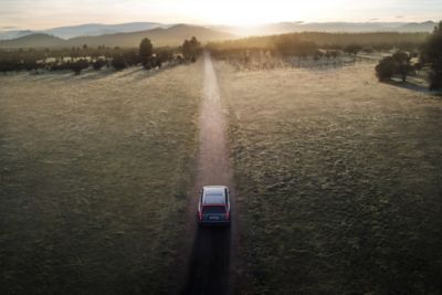 Hyundai IONIQ 9 circulant sur une route de campagne ensoleillée avec des montagnes à l’horizon.