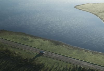 IONIQ 9 circulant sur une route de campagne près d’un lac.
