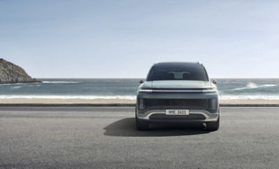 The all-electric Hyundai IONIQ 9 seen from the front parked by the sea.