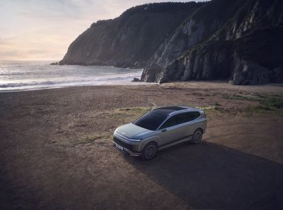 De IONIQ 9 staat geparkeerd aan zee.