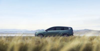 Side view of the IONIQ 9 as it drives through the maize fields.