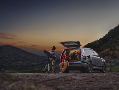 Parked IONIQ 9 with tailgate open using V2L for telescope for stargazing.