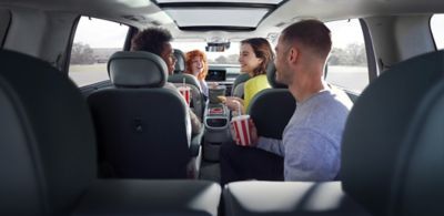 Twee jonge mannen en twee jonge vrouwen met drinkbeker in de hand en vrolijk pratend met elkaar, zittend op de Relaxation Seats in de Hyundai IONIQ 9.