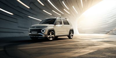 The new Hyundai INSTER small electric car parked in a tunnel with dramatic lighting.