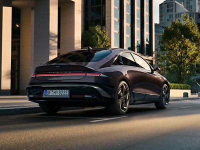 Driekwart achteraanzicht stilstaande Hyundai IONIQ 6 in een stedelijke omgeving.