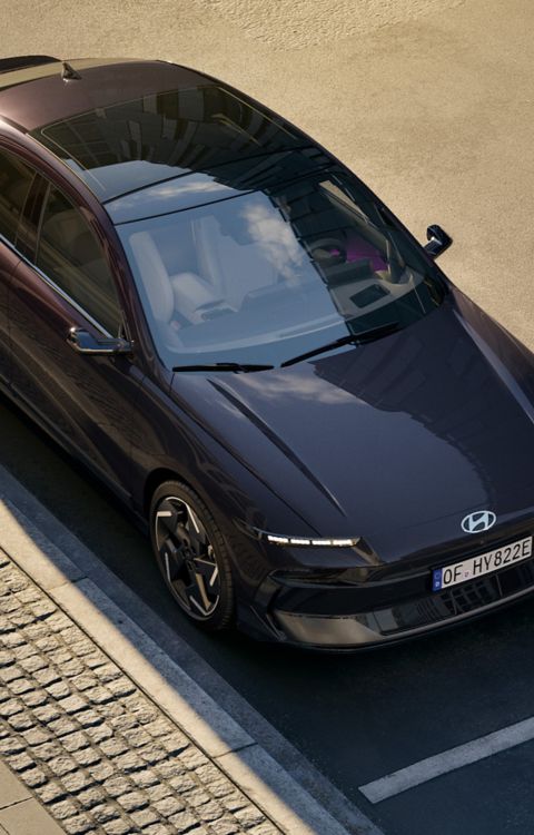 HYUNDAI IONIQ 6 viewed from above driving along a sunlit road, highlighting its streamlined shape and clean lines.