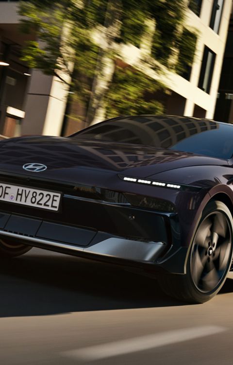 HYUNDAI IONIQ 6 in motion on a city street, captured from a low rear angle emphasizing speed, performance, and dynamic design.