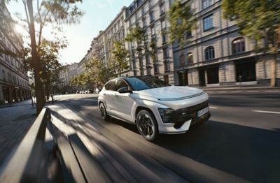 The all-new KONA Electric N Line in Serinity White Pearl driving through a city.