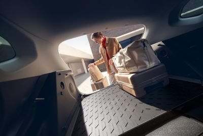 A woman loading luggage on a trunk mat.