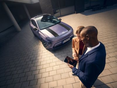 A man and woman standing in front of the Hyundai KONA Electric.