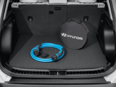 Blue charging cable and its Hyundai-branded case in the trunk of a Kona Electric.