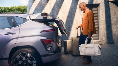 The Hyundai KONA Electric in blue parked in front of building. 