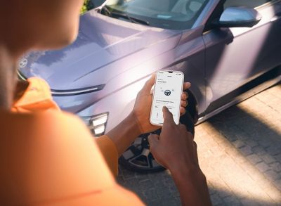 Over the shoulder perspective, a person  is checking  total distance travelled this month on app.