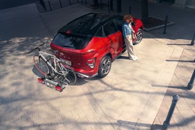 A woman looking at her bicycle, which is fixed to the KONA Electric bike carrier for tow bars.