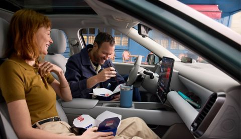 A man and a woman eating take out food in the front seats of the Hyundai IONIQ 3.