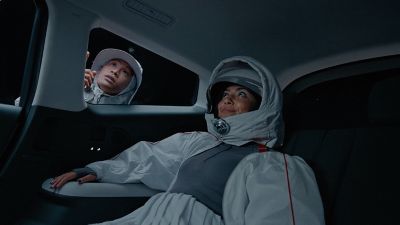 Man stood outside and woman inside the IONIQ 9 in spacesuits