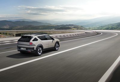 Hyundai NEXO driving on a highway with hills and a bridge in the background.