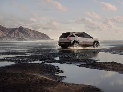 Een waterstof-elektrische Hyundai NEXO SUV rijdend op het strand en van opzij gezien.