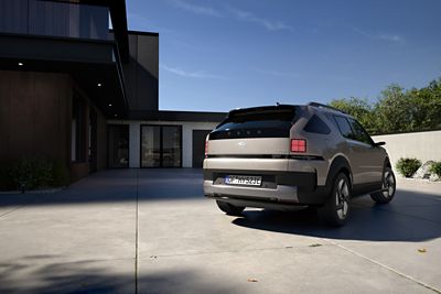 The all-new Hyundai NEXO seen from the rear, parked in a wide driveway in front of a modern house.