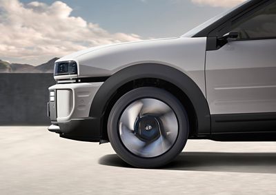 Close-up view of alloy wheels and headlamp of the Hyundai NEXO SUV seen from the side.	