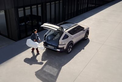 A person loading a cello case into the rear hatch and cargo space of the Hyundai NEXO.