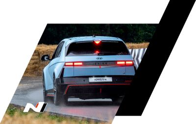 The all-electric Hyundai IONIQ 5 N driving on a race track with some trees. 
