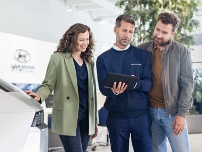 Customers exploring Hyundai vehicle options and ownership benefits with a Hyundai dealership consultant.