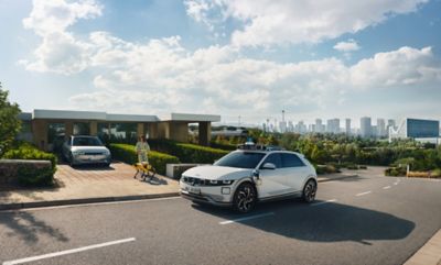 An all-electric Hyundai IONIQ 5 robotaxi on the street next to a house.