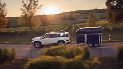 Hyundai SANTA FE Hybrid with 2000 kg of towing capacity towing a horse trailer on a country road.