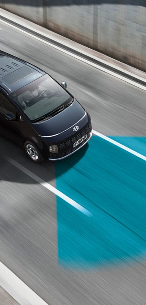 Hyundai STARIA van driving on a highway with an adjacent lane highlighted to indicate driver‑assistance functionality.