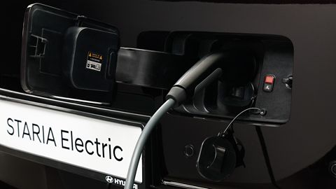 Close-up of the STARIA Electric charging port with cable connected for electric charging.