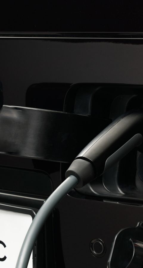 Close-up of the STARIA Electric charging port with cable connected for electric charging.