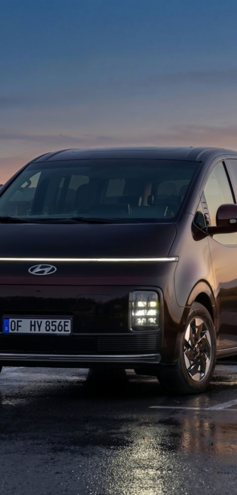 Hyundai i30 seen from rear three-quarter driving on a city street in front of modern buildings.