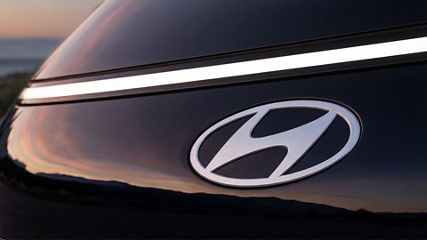 Hyundai STARIA Electric front emblem detail with LED light strip at sunset.